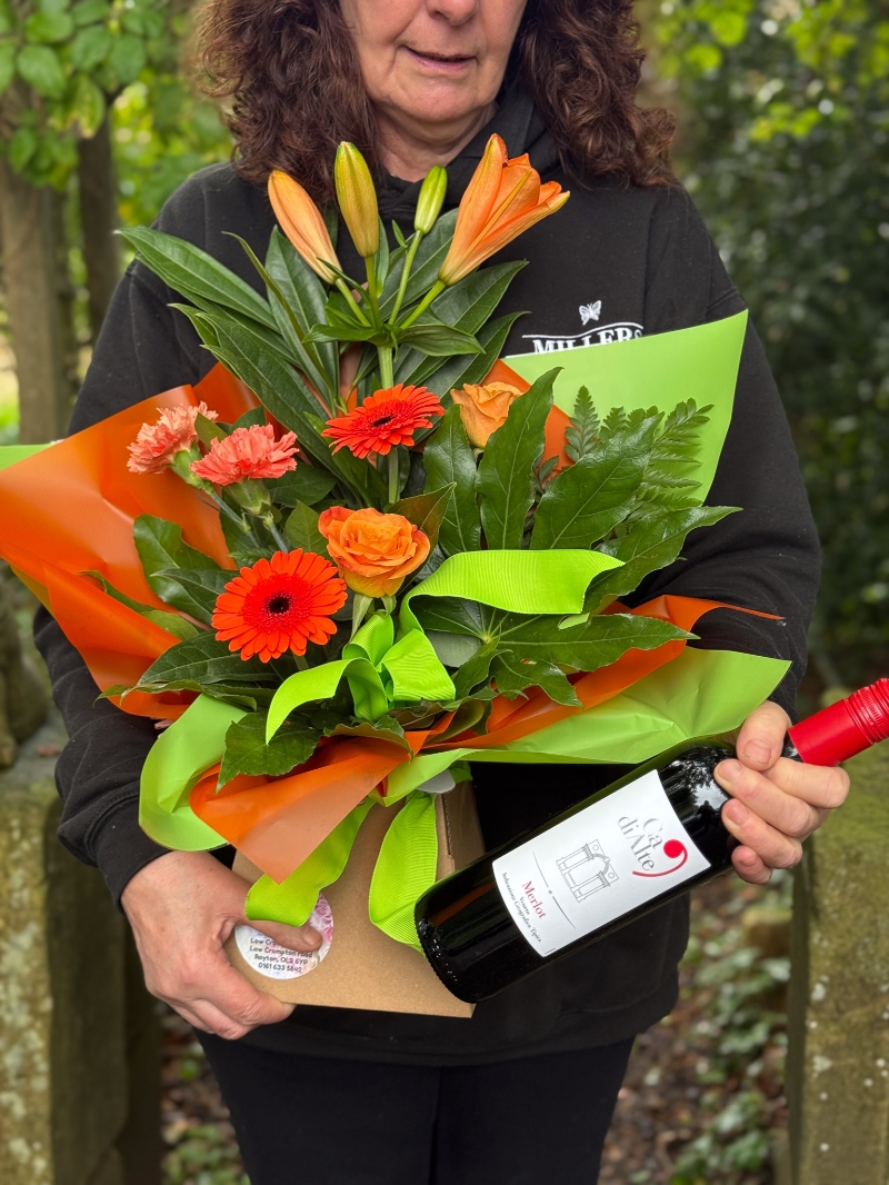 Petite bright flower gift box with orange lilies, germini, roses, carnations and fresh green foliage