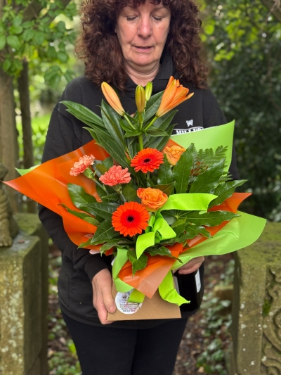 Petite bright flower gift box with orange lilies, germini, roses, carnations and fresh green foliage