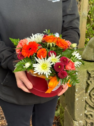 Autumn Glow orange and burgundy hatbox flower arrangement by Millers Floral Design in Royton