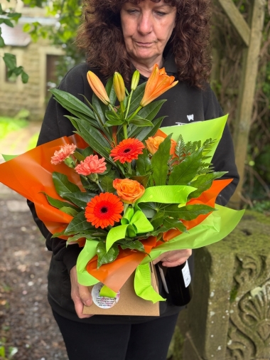 Petite bright flower gift box with orange lilies, germini, roses, carnations and fresh green foliage