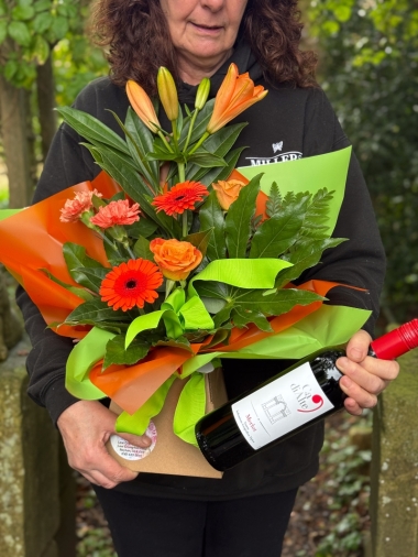 Petite bright flower gift box with orange lilies, germini, roses, carnations and fresh green foliage